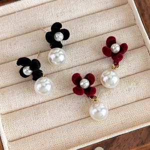 Close-up of vintage red and black velvet flower earrings with round white pearl drops