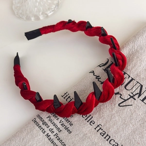 Detail of red velvet headband with black spikes and twisted texture for punk style