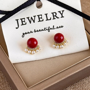 Macro view of fan-shaped earrings with red pearl, white pearls and gold metal plating