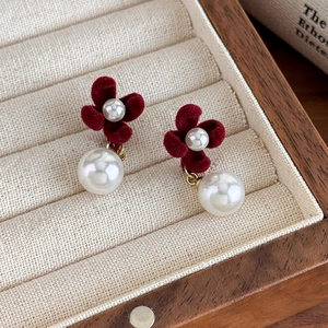 Close-up of vintage red velvet flower earrings with white pearls in a wooden jewelry box