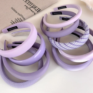Flat lay of multiple purple headbands in velvet, woven, and leather textures