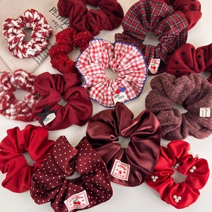 New Year red plush scrunchie set with assorted fabrics, pearls, and bows on white surface