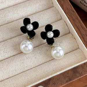 Detail of red velvet flower earrings with classic white pearls and gold metal accents