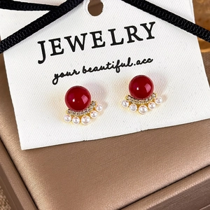 Close-up of red bead earrings with mini pearls and zircon on gold base jewelry