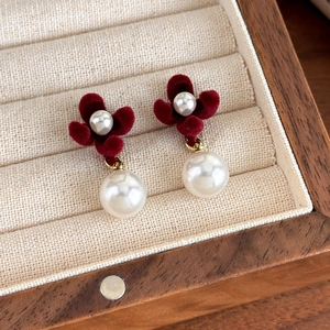 Detail of red velvet flower earrings with large white pearls on a jewelry tray