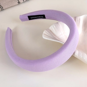 Close-up of a handmade lilac padded headband with soft knit texture and brand label