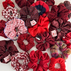 Detailed view of assorted red scrunchies in velvet, satin, and knitted fabrics