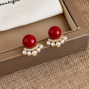 Detailed macro view of vintage red pearl earrings with gold fan-shaped crystal accents