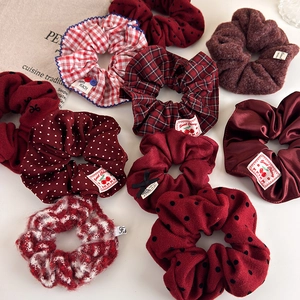 Flat lay of diverse red scrunchies in velvet and satin with elegant cherry woven labels