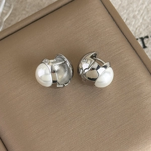 Gros plan détaillé des boucles d'oreilles perles françaises sur boîte cadeau beige