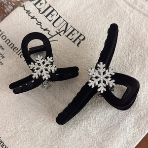 Elegant black velvet snowflake hair claws with rhinestones on beige fabric background
