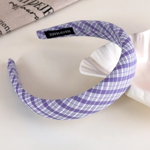 Detailed macro view showing the handmade label on purple plaid fabric headband