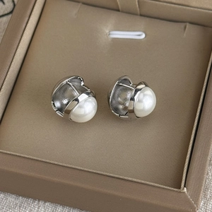 Détail macro de boucles d'oreilles en métal argenté poli avec une grande perle blanche