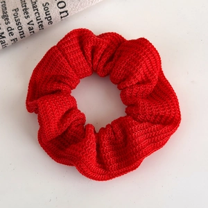 Close-up of red knitted plush scrunchie showing detailed yarn texture and soft folds