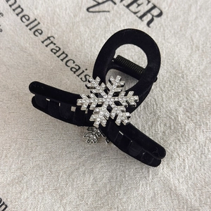 Close-up of a black velvet hair claw clip with a sparkling rhinestone snowflake detail