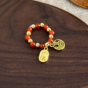 Détail de perles d'agate rouge et pendentifs dorés avec caractères Fu sur bois