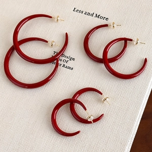Three-size set of elegant red enamel C-shape hoop earrings on a minimalist book background