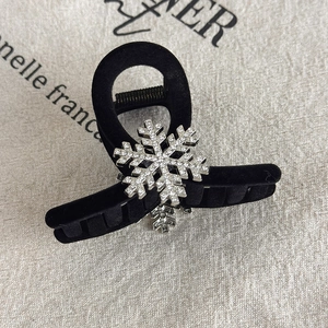 Detail of a black velvet hair claw with a sparkling rhinestone snowflake design