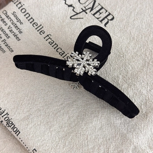 Detail showing crystal snowflake ornaments on a black velvet hair claw clip