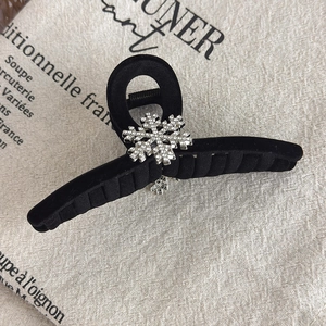 Macro detail of black velvet hair claw featuring a sparkling rhinestone snowflake ornament