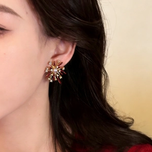 Elegant gold flower earrings with burgundy enamel and a central pearl on a model