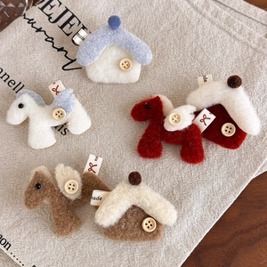 Close-up of felt horse and house brooches with wooden buttons on linen fabric