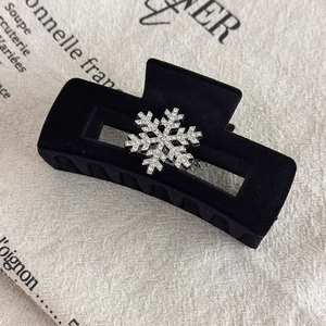 Detail of a black velvet hair claw clip with a sparkling rhinestone snowflake decoration