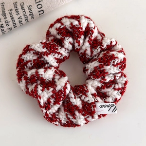 Detail of red and cream knitted scrunchie with silver metallic thread and logo tag
