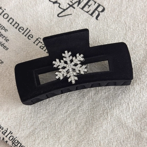 Macro shot of black velvet claw clip with sparkling silver rhinestone snowflake detail