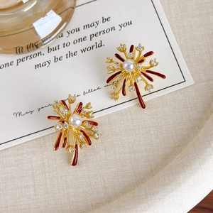 Macro shot of gold firework stud earrings with red enamel and shimmering cubic zirconia