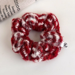 Close-up of red and white plush knitted scrunchie with soft texture and side brand label