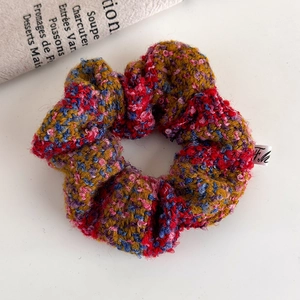 Detailed macro view of a red and blue tweed knitted scrunchie on a white surface