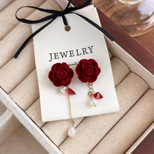 Gros plan de boucles d'oreilles rose en velours rouge avec perles sur carte de bijoux