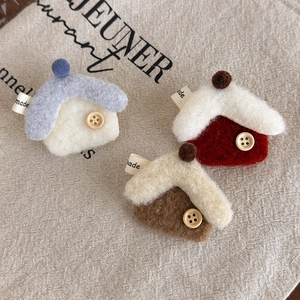 Detail of wool felt house hair clips with wood buttons and fuzzy balls in three colors