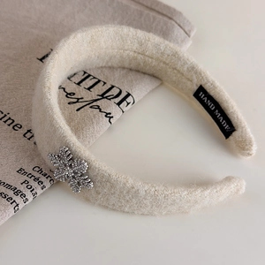 Détail du serre-tête en peluche blanc cassé avec papillon en strass et étiquette