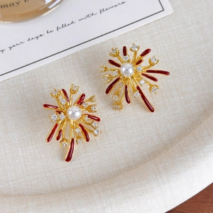 Detailed close-up of firework earrings with red enamel and central white pearls
