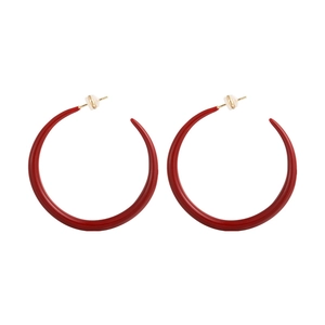 Close-up of red enamel C-shaped hoop earrings with gold posts and clear backings