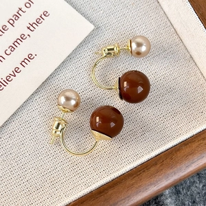 Orecchini vintage con perle marrone caramello e champagne su sfondo di tessuto ruvido