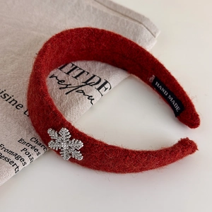 Gros plan détaillé d'un serre-tête en laine rouge avec flocon de neige en strass brillant