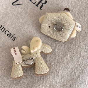 Detail of the handmade plush brooch back showing the metal pin and woven textile label