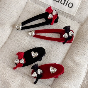 Close-up of velvet hair clips with rhinestone hearts and bows in red and black
