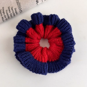 Detailed close-up of knitted scrunchie with vibrant red and navy blue contrasting edges
