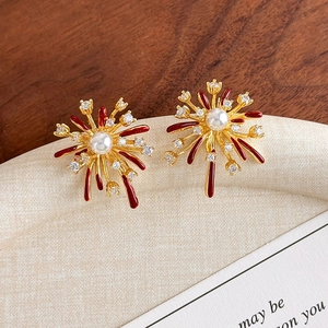 Macro detail of firework stud earrings with red enamel rays and a central faux pearl