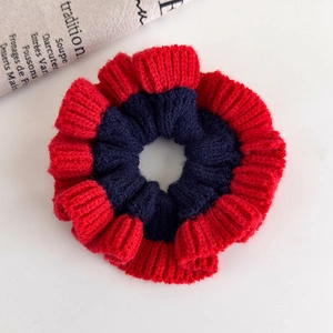 Detail of red and navy knitted scrunchie showing ribbed texture and wave edge