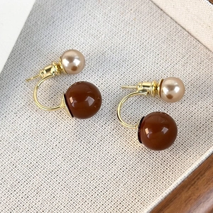 Dettaglio di eleganti orecchini a doppia perla champagne e caramello su oro