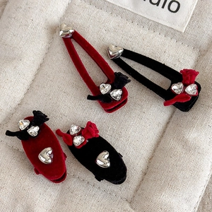 Close-up of velvet bow hair clips with silver heart pendants and sparkling rhinestones