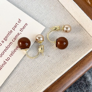 Dettaglio dei retro orecchini a U con perle color champagne e marrone lucido