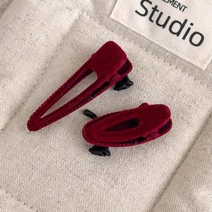 Close-up of vintage dark red velvet hair clips with elegant texture on a beige background