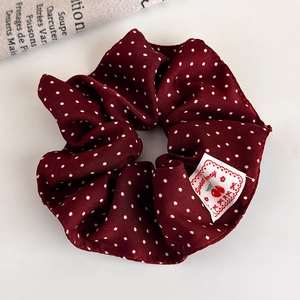 Detailed macro view of dark red polka dot scrunchie with sweet berry woven label