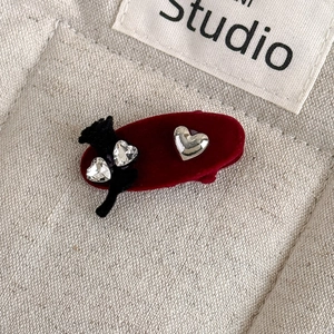 Detailed close-up of a burgundy velvet hair clip with rhinestones and heart charms